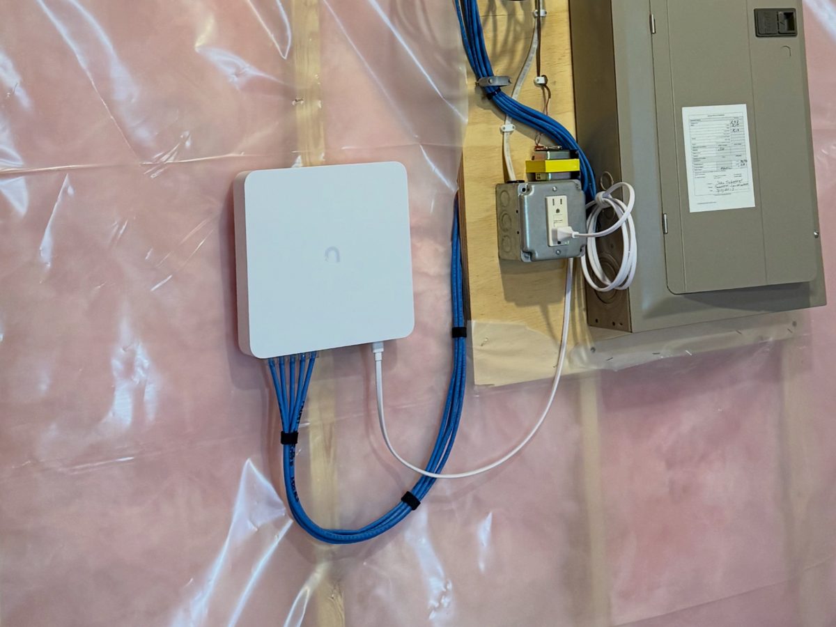 UniFi Protect recorder with bundled camera cables in an unfinished basement