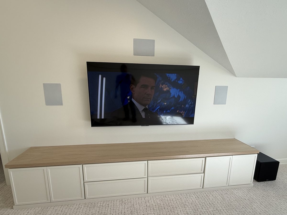 Wall-mounted TV with in-wall speakers above a media cabinet in a Sioux Falls, SD home